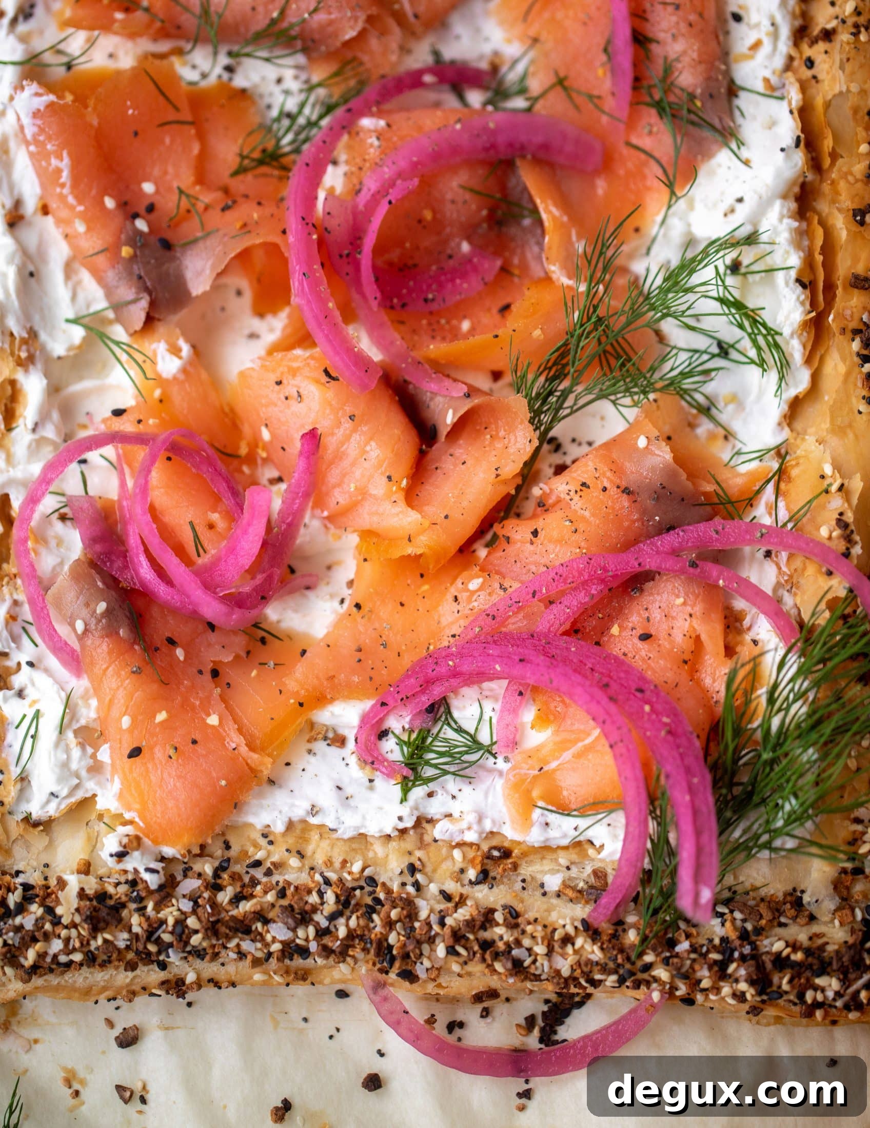 This everything smoked salmon tart is perfect for brunch! Puff pastry sprinkled with everything seasoning, slathered in cream cheese and topped with salmon.
