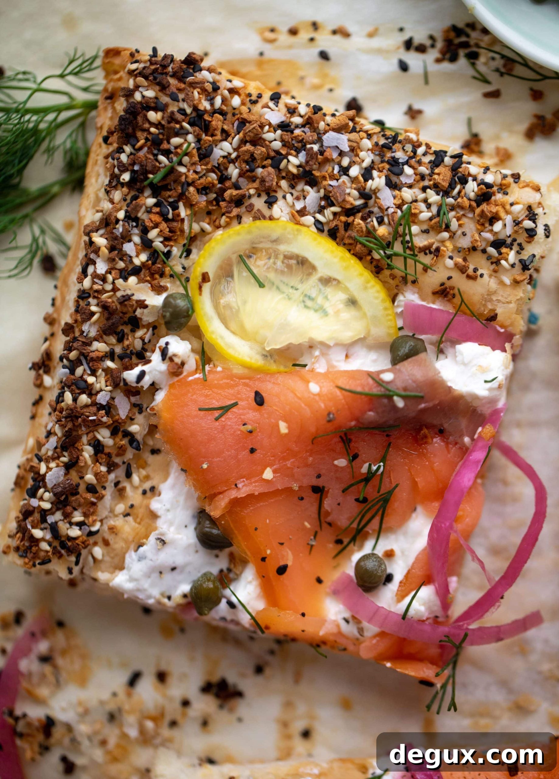 This everything smoked salmon tart is perfect for brunch! Puff pastry sprinkled with everything seasoning, slathered in cream cheese and topped with salmon.