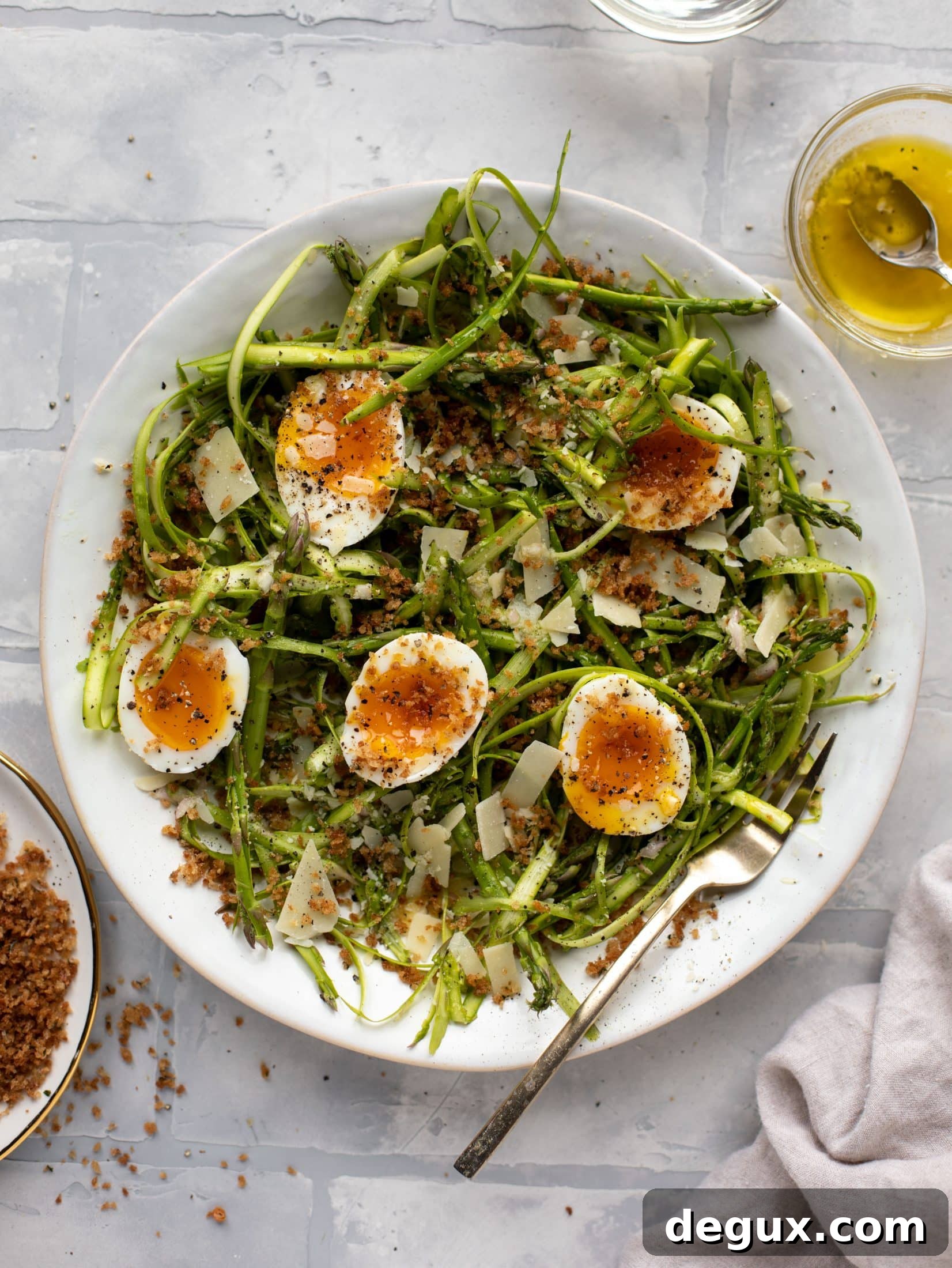 This shaved asparagus salad is tossed with a delicious parmesan vinaigrette, then topped with soft boiled eggs and finished with crunchy garlic breadcrumbs!