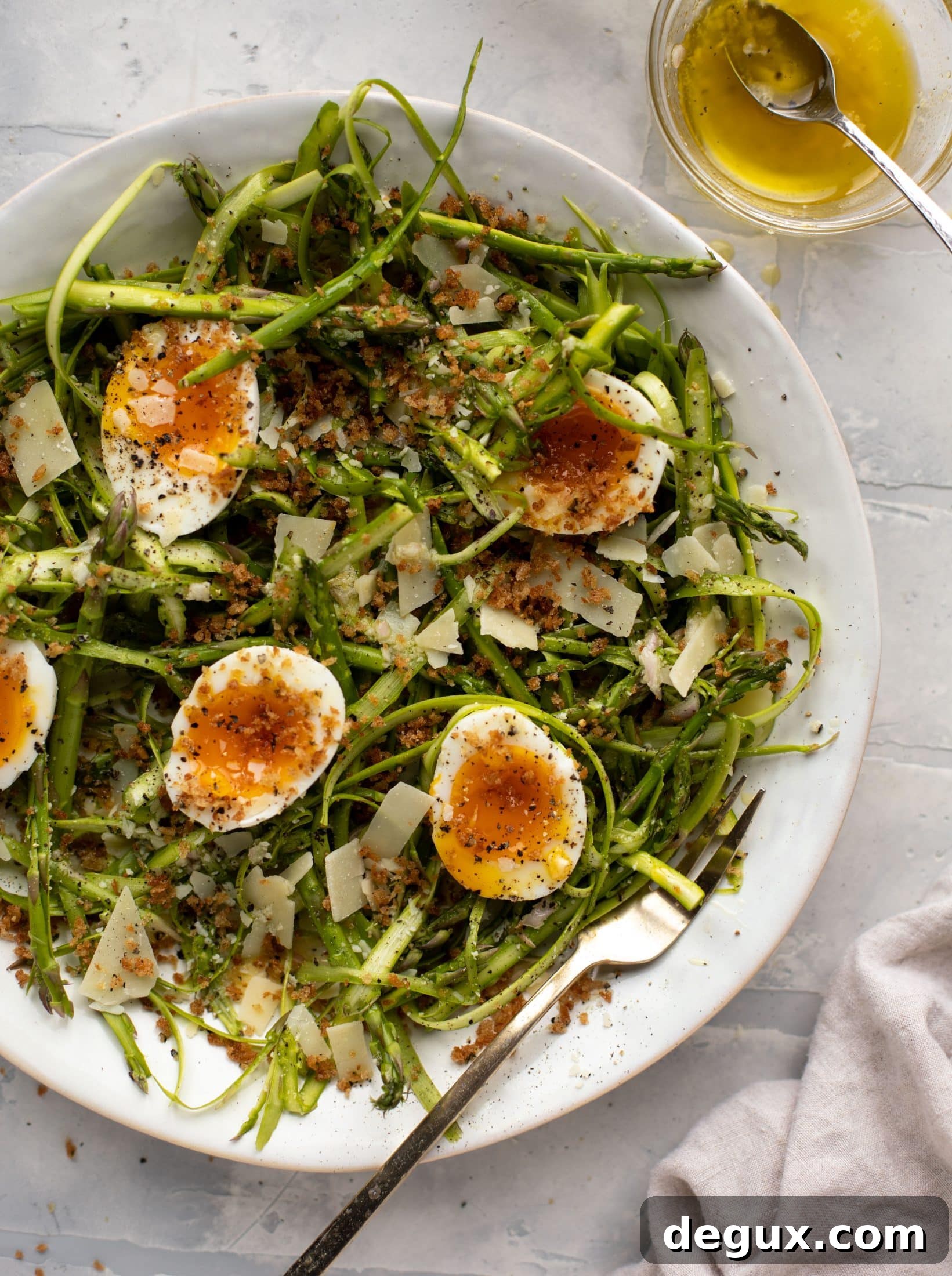 This shaved asparagus salad is tossed with a delicious parmesan vinaigrette, then topped with soft boiled eggs and finished with crunchy garlic breadcrumbs!