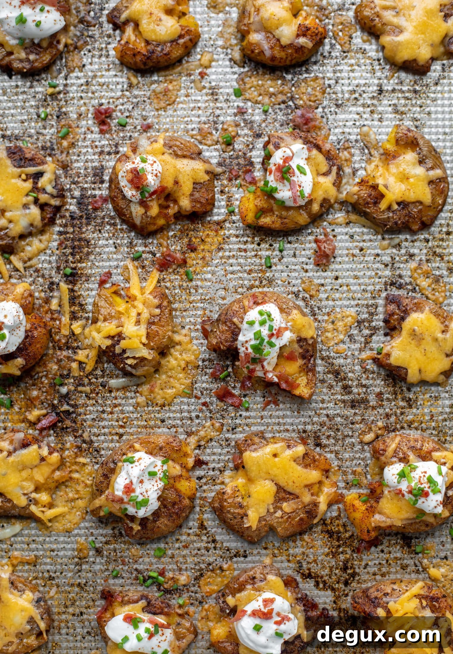 Chipotle cheddar smashed potatoes on a baking sheet. These super crispy chipotle cheddar smashed potatoes are the best side dish. A little spicy and smothered in cheese, they are irresistible.