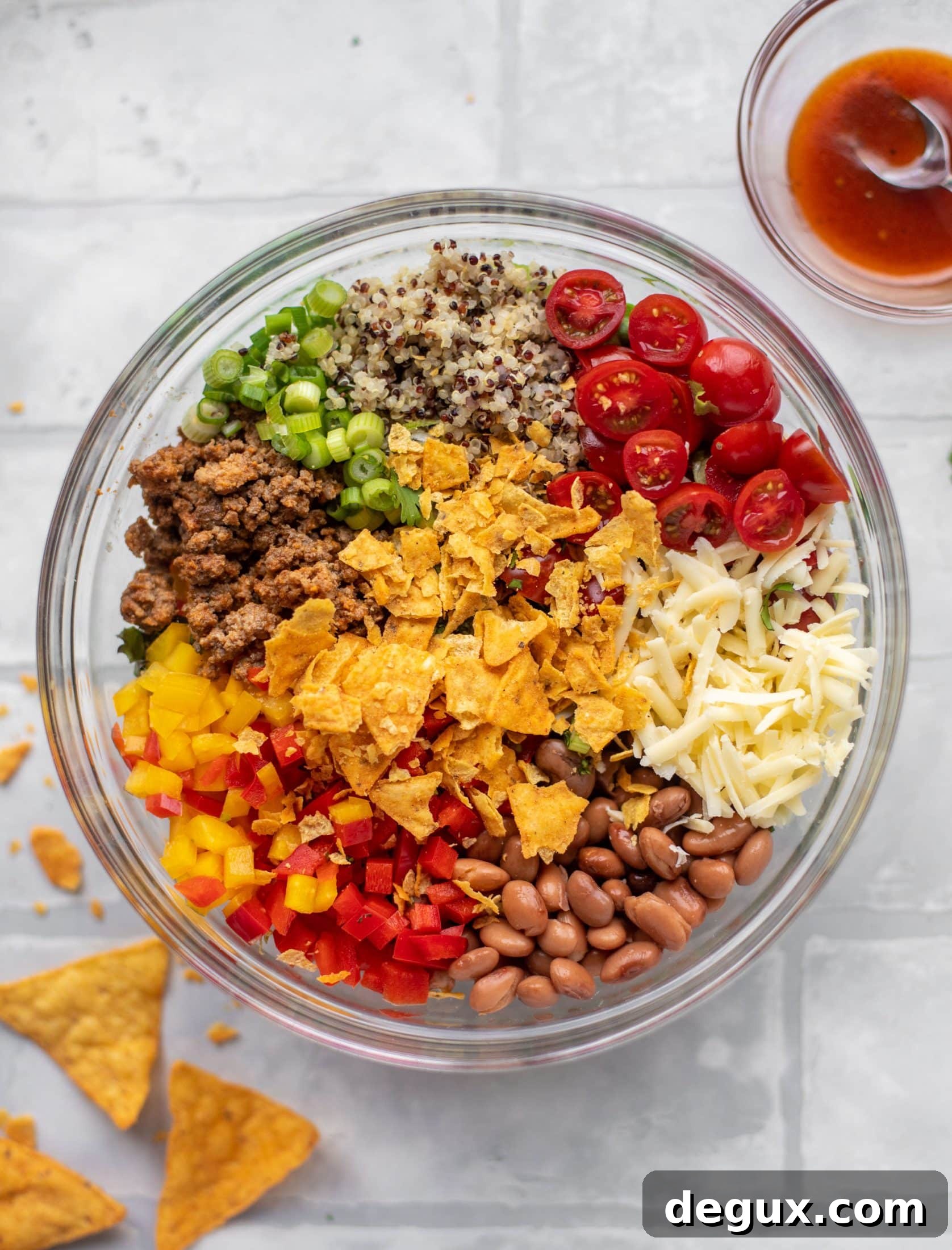taco beef, scallions, quinoa, tomatoes, cheese, beans, peppers, chips in a bowl