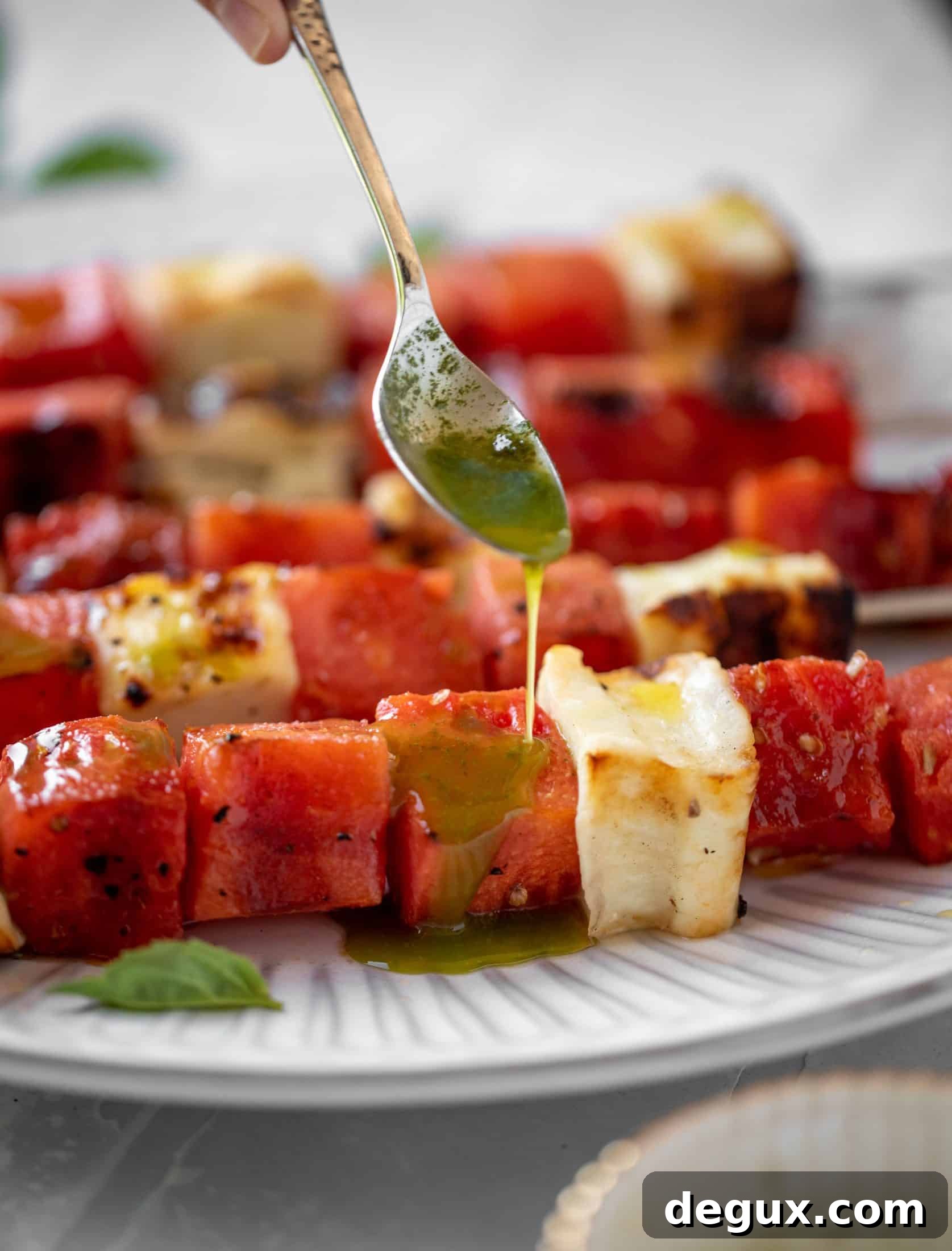 drizzling mint basil oil on grilled watermelon halloumi skewers