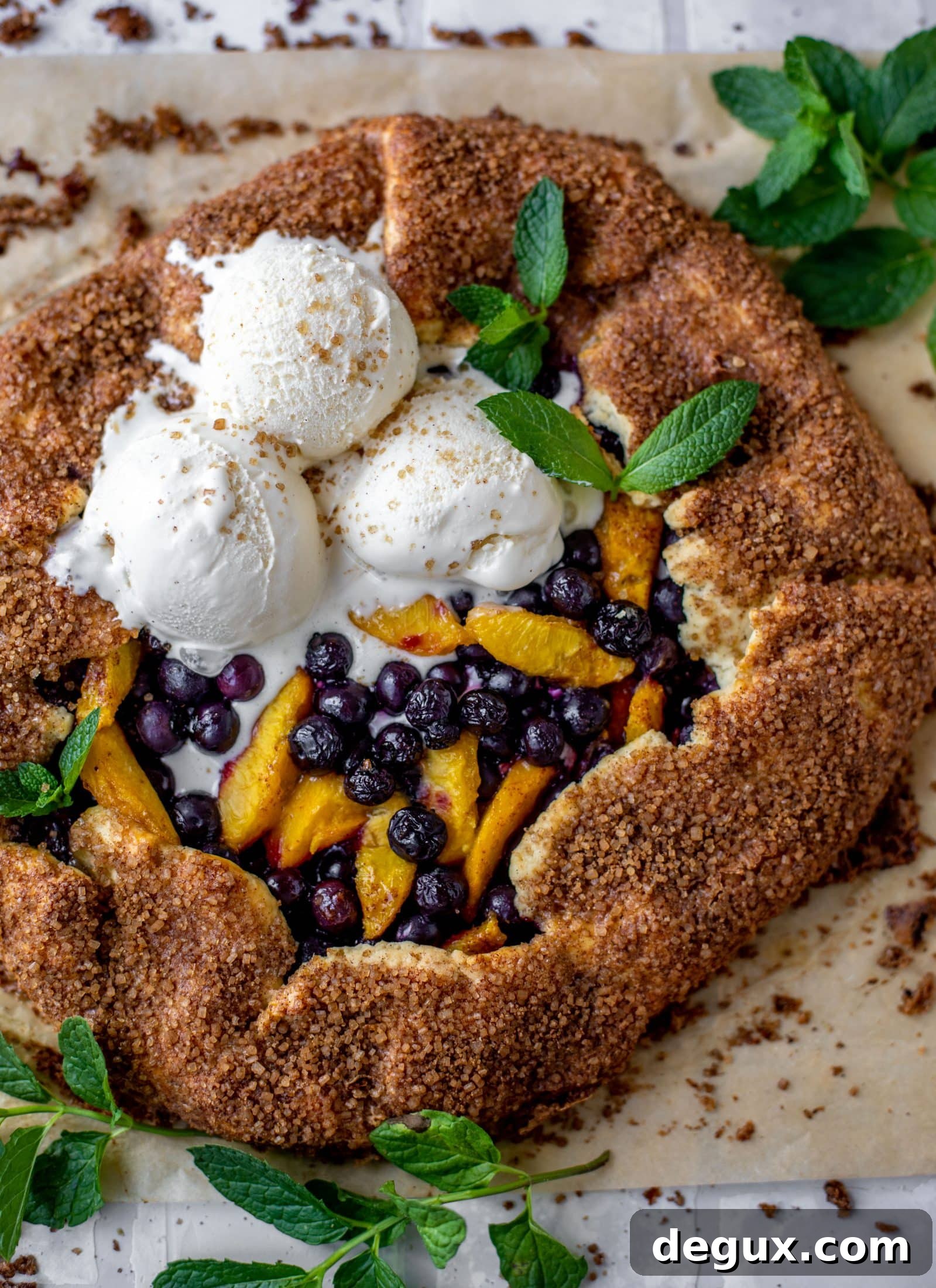 blueberry peach galette with cinnamon sugar galette topped with ice cream and fresh mint