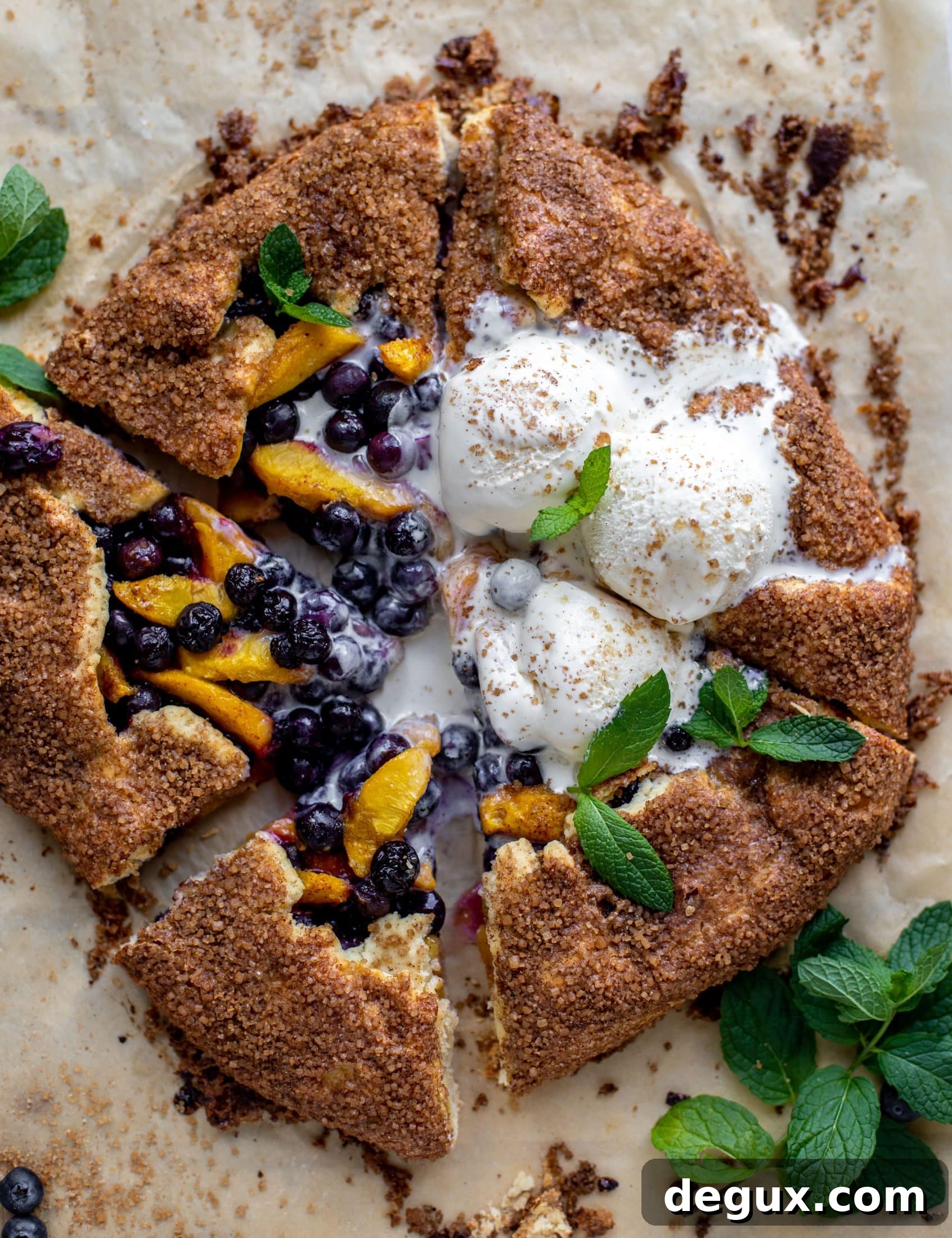 sliced blueberry peach galette with cinnamon sugar galette topped with ice cream and fresh mint