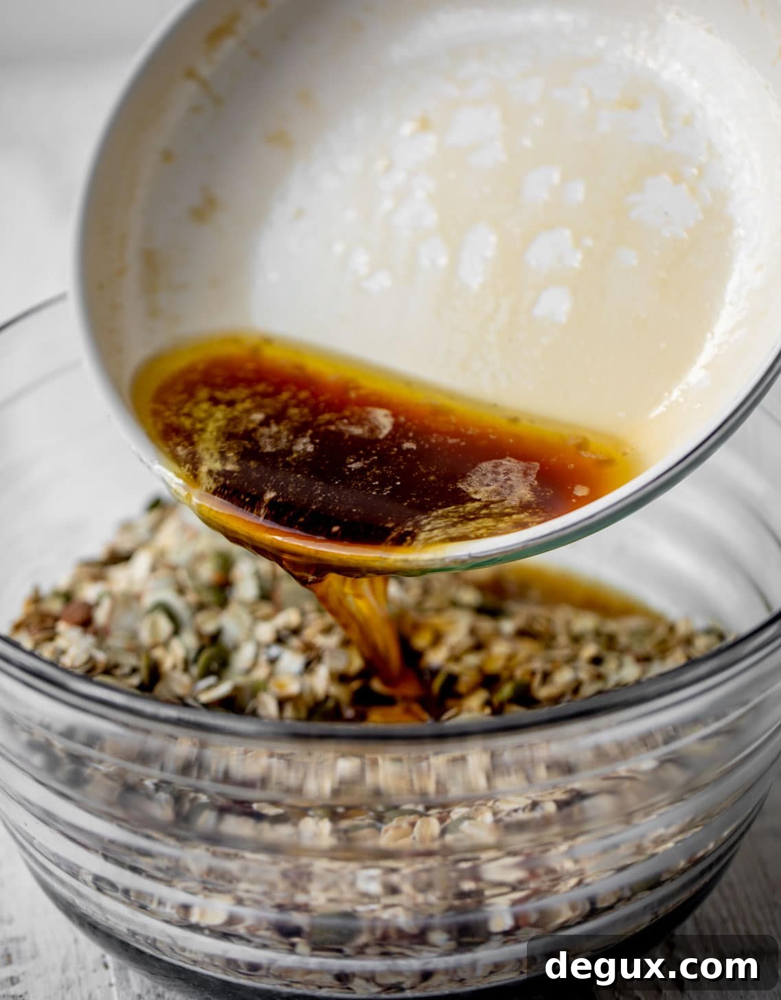 Salted Maple Granola Recipe for Crunchy Homemade Morning Oats 4 pouring maple syrup into the granola