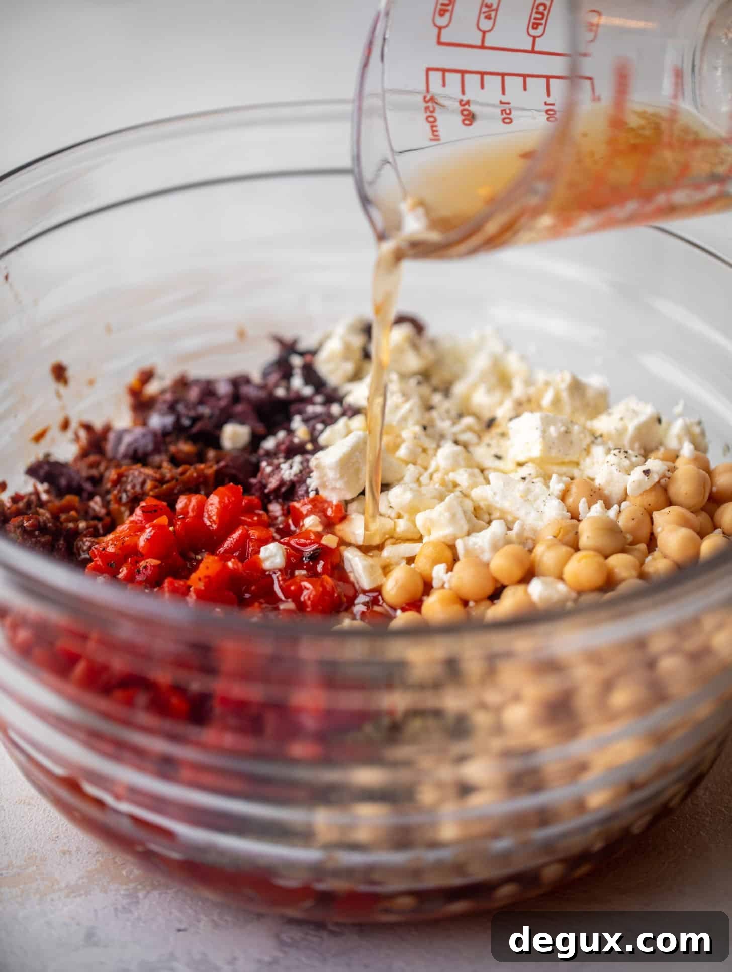 Make-Ahead Mediterranean Marinated Chickpea Salad 4 pouring vinaigrette on ingredients