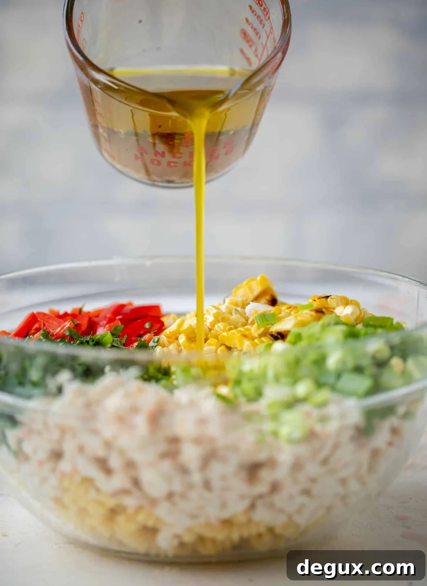 pouring dressing on grilled corn and crab pasta salad