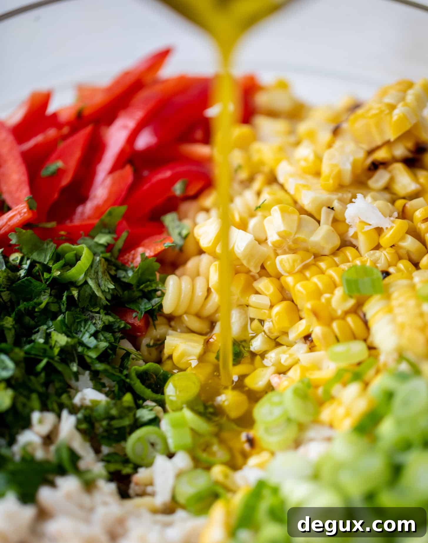 pouring dressing on grilled corn and crab pasta salad