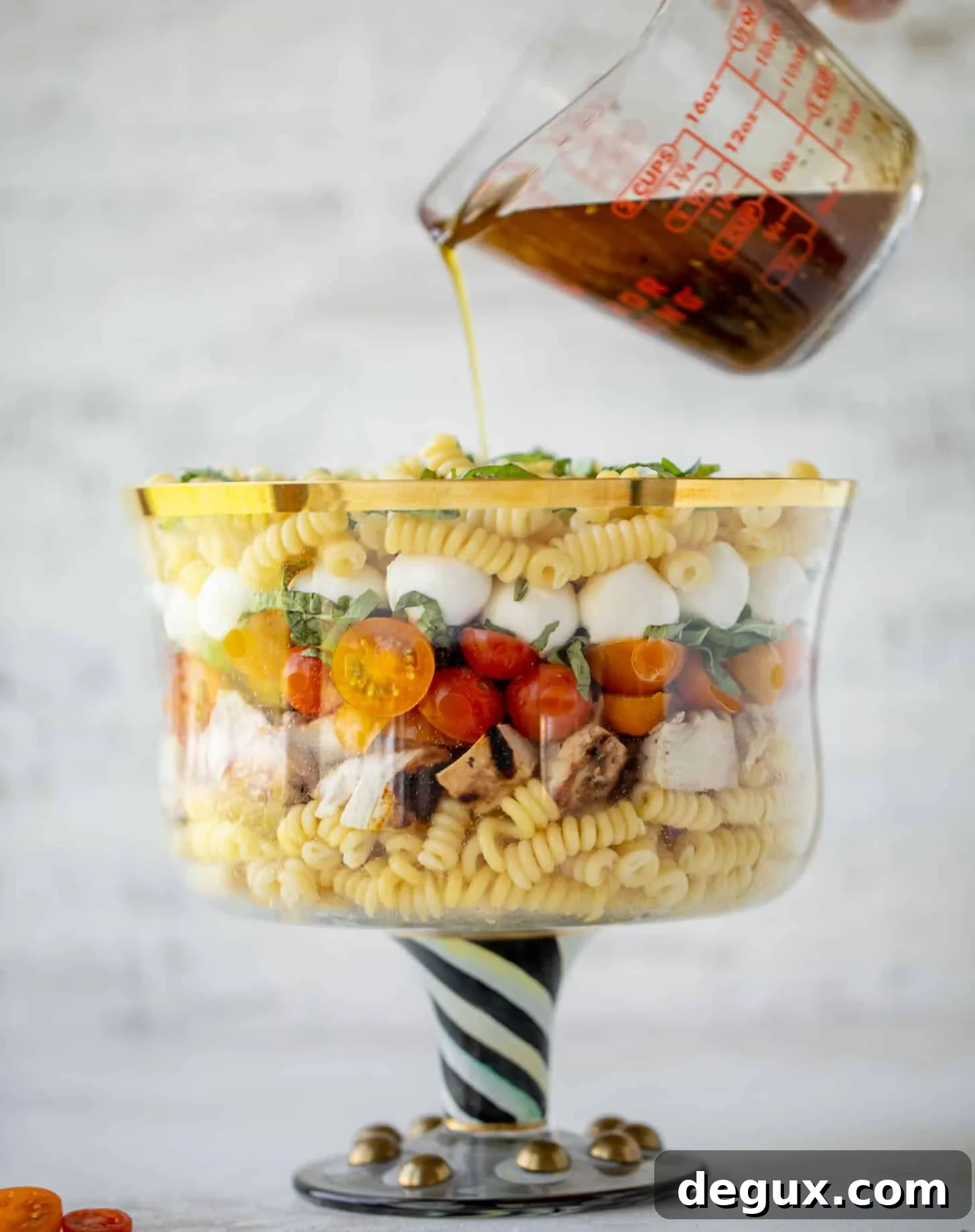 pouring dressing on grilled chicken caprese pasta salad