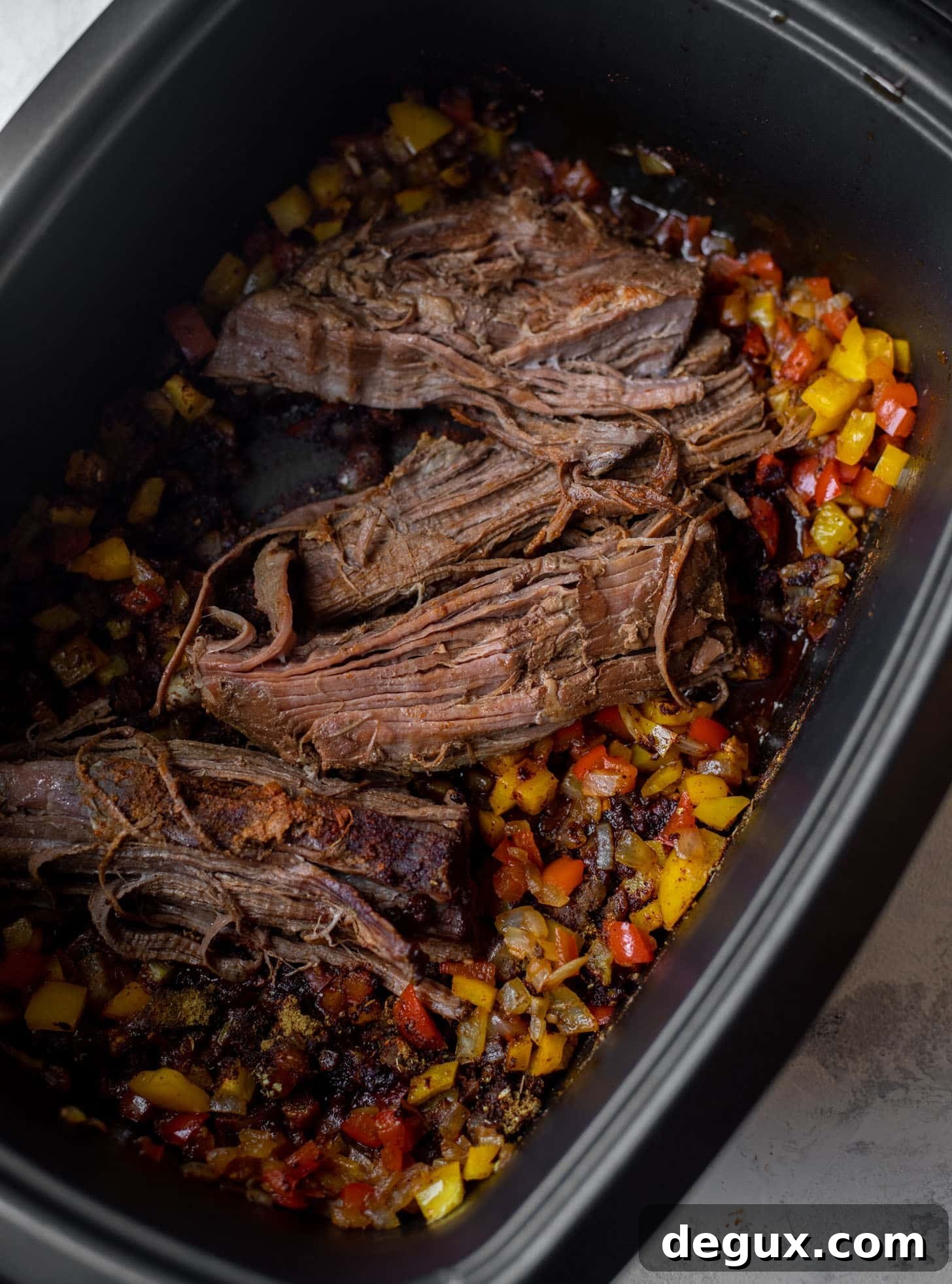 slow cooker with brisket and peppers and onions