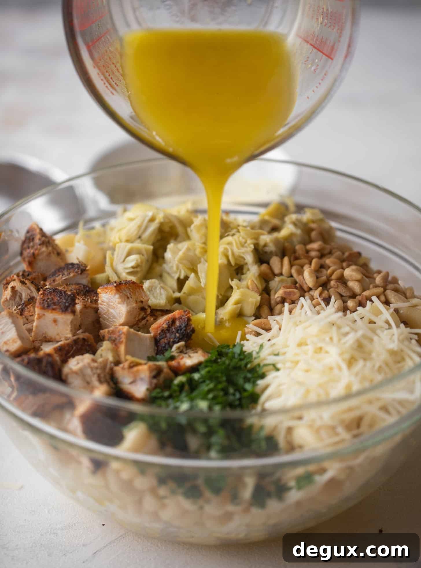 Zesty Lemon Chicken & Artichoke Pasta Salad Recipe 6 pouring dressing on lemon chicken artichoke pasta salad