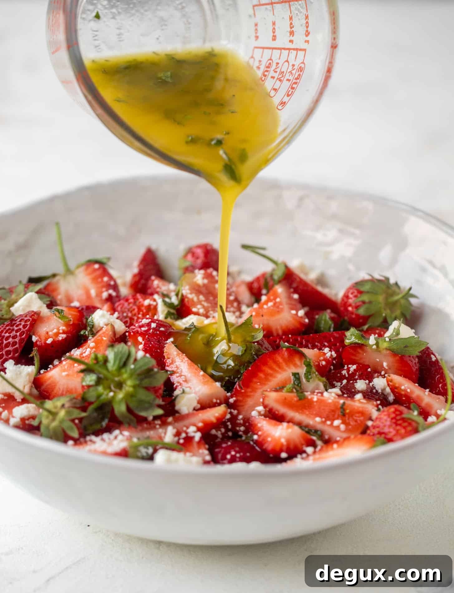 pouring champagne dressing on strawberry salad
