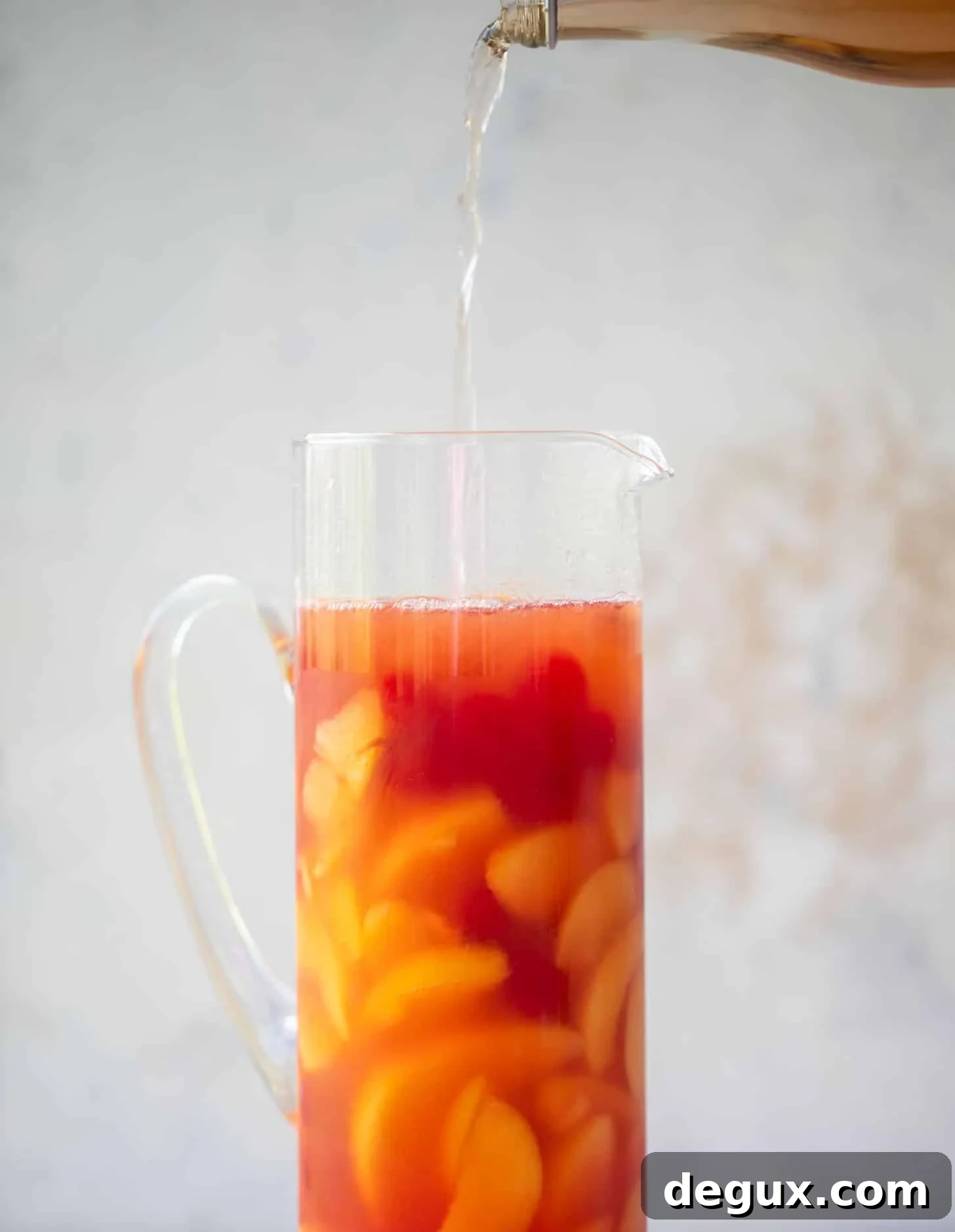 Summer Tequila Fruit Punch Recipe for Refreshing Backyard Parties 4 pouring sparkling rose in a pitcher